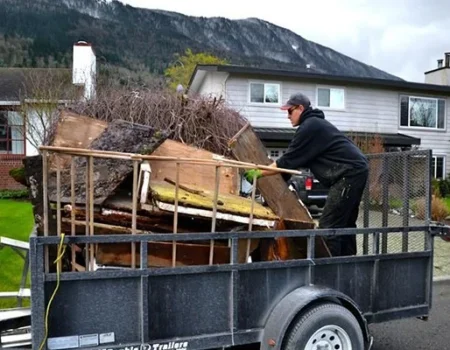 Worker loading junk onto a trailer as part of a hauling service