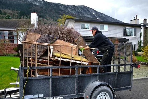 Worker loading junk onto a trailer as part of a hauling service