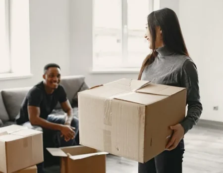 A smiling couple packing boxes in their living room, preparing for a smooth and organized move to a new home.