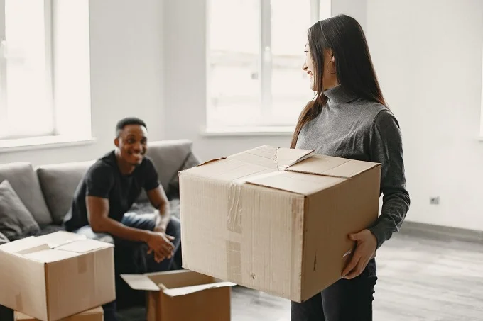 A smiling couple packing boxes in their living room, preparing for a smooth and organized move to a new home.