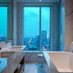 Kohler round enameled sink on a marble countertop with sunlight streaming through a window, enhancing bathroom elegance.