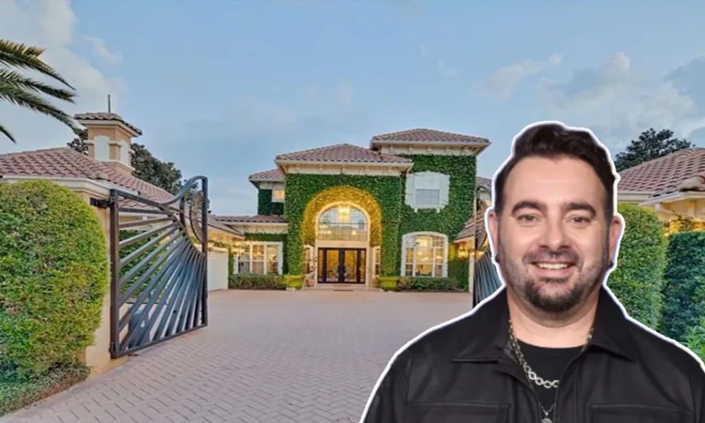 Chris Kirkpatrick House front view showing the *NSYNC star smiling before his grand ivy-covered mansion with gated driveway and Mediterranean design.