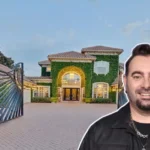 Chris Kirkpatrick House front view showing the *NSYNC star smiling before his grand ivy-covered mansion with gated driveway and Mediterranean design.