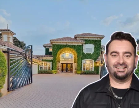 Chris Kirkpatrick House front view showing the *NSYNC star smiling before his grand ivy-covered mansion with gated driveway and Mediterranean design.