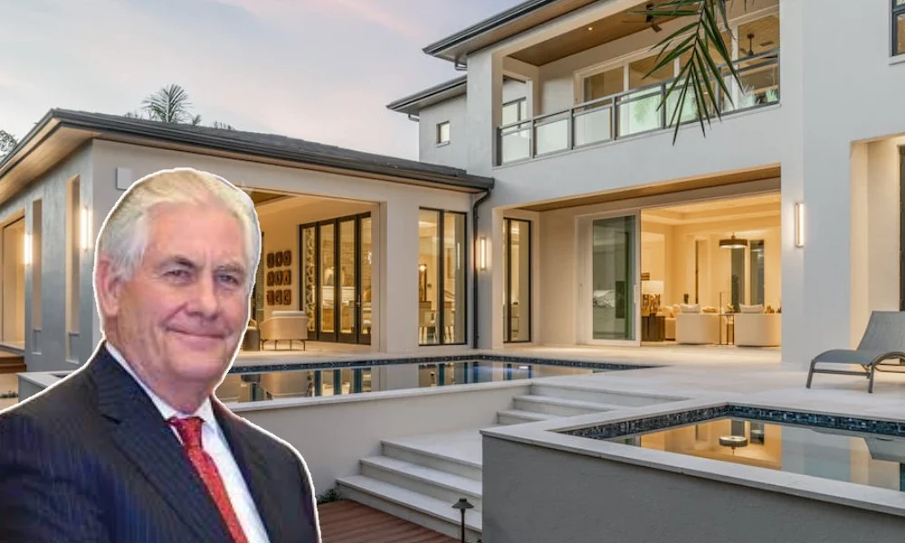 Portrait of Rex Tillerson in a formal suit with luxury homes in the background.
