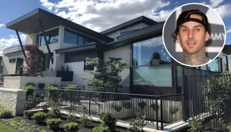 A close-up shot of the Travis Barker House showing its sleek architectural lines, flat roofs, and dark window frames, contrasted against light stone brick walls and manicured front landscaping. A circular headshot photo of a smiling Travis Barker wearing a black backwards cap is overlaid in the top right corner.