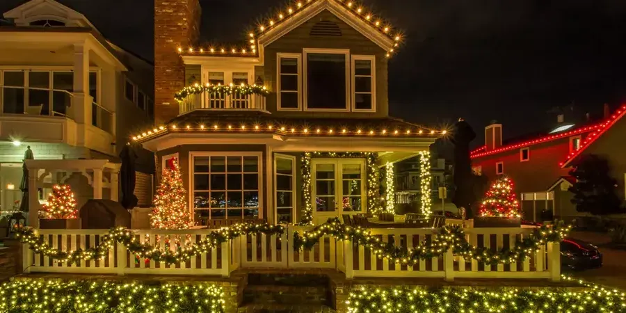 Outdoor christmas decorations with warm white lights on a house at night