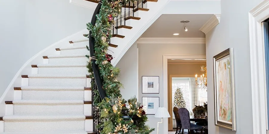 Christmas staircase decor ideas with garland and warm fairy lights on the banister